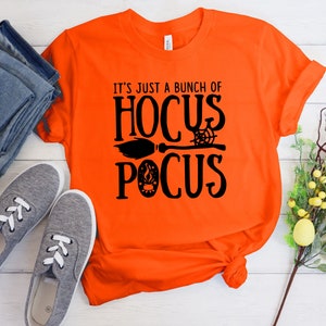 May include: Orange t-shirt with black text that reads "It's just a bunch of Hocus Pocus" with a broom and spider web graphic.