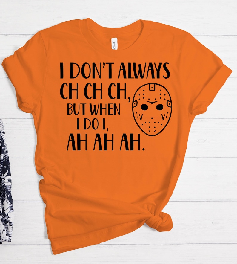 K&ouml;nnte beinhalten: Orangefarbenes T-Shirt mit schwarzem Text, der "Ich mache nicht immer ch ch ch, aber wenn ich es tue, ah ah ah." lautet. Neben dem Text befindet sich eine schwarz-wei&szlig;e Hockeymaske.