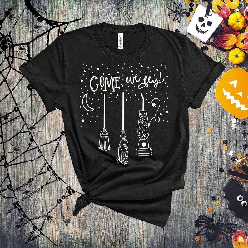May include: Black t-shirt with white text that reads "COME, we fly!" and a graphic of three broomsticks and a lava lamp.