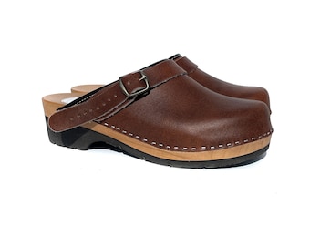May include: Brown leather clogs with a buckle strap and a wooden sole.