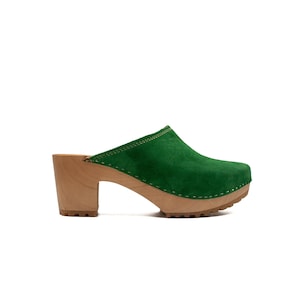 Puede incluir: Zuecos de tac&oacute;n de ante verde con plataforma y tac&oacute;n de madera. Los zuecos tienen la punta cerrada y una tira trasera.