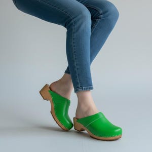 Tamancos de couro verde, sapatos de madeira suecos clássicos para mulheres.