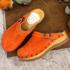 Tamancos femininos artesanais em couro laranja, estilo mule vintage de madeira, ideais para uso casual e diário.