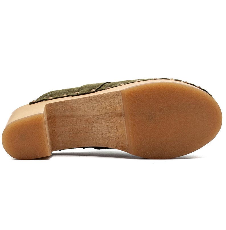 May include: Green suede clog with a wooden platform sole. The sole is made of natural wood and has a brown color.