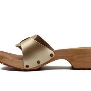 May include: Gold leather heeled sandals with a wooden platform and a buckle detail.