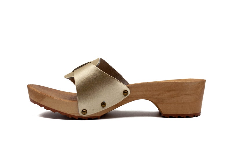 May include: Gold leather heeled sandals with a wooden platform and a buckle detail.