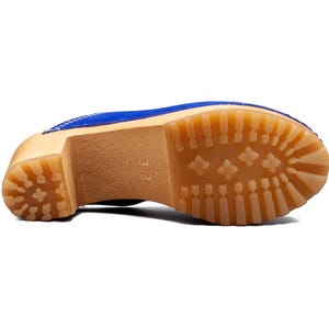 May include: The bottom of a blue suede clog with a wooden sole and a rubber tread.