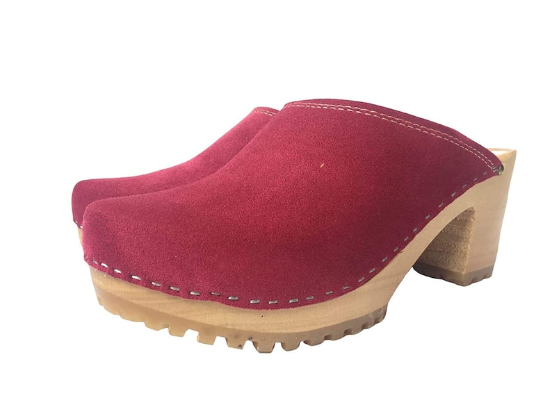 May include: Red suede clogs with a wooden platform and a high heel. The clogs have a stitched seam around the top edge.
