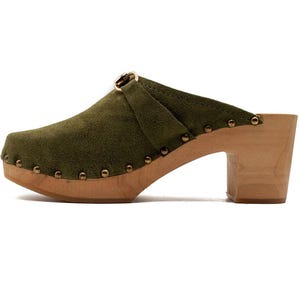 May include: Green suede clog with a wooden heel and a gold buckle. The clog has a studded design around the sole.