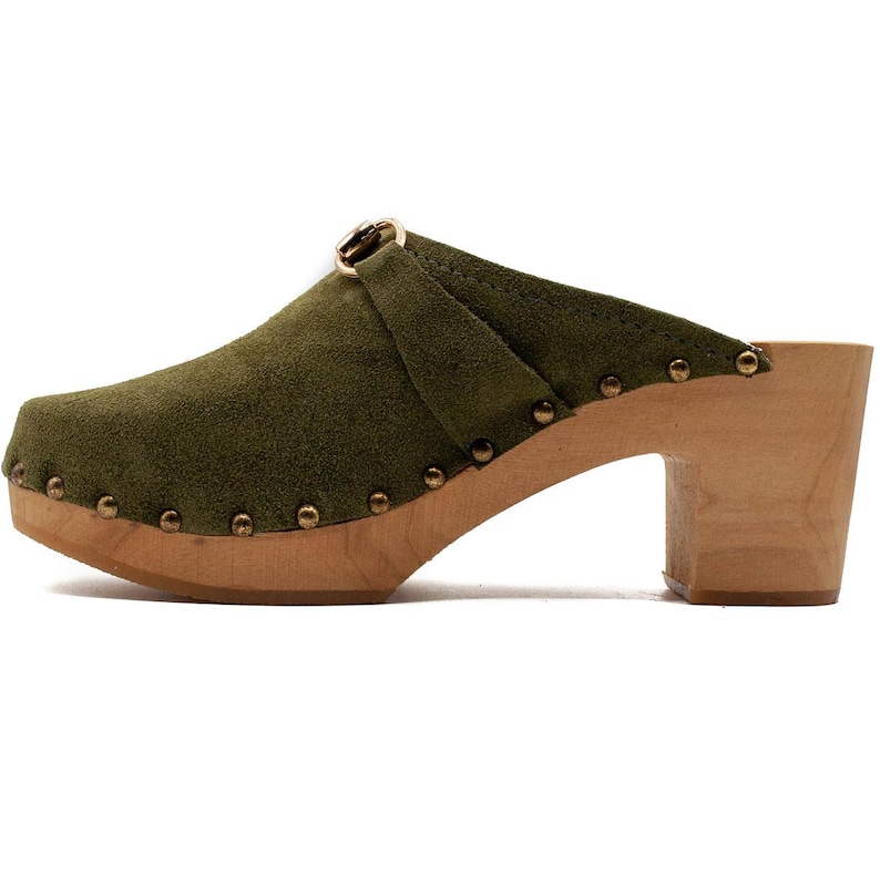 May include: Green suede clog with a wooden heel and a gold buckle. The clog has a studded design around the sole.