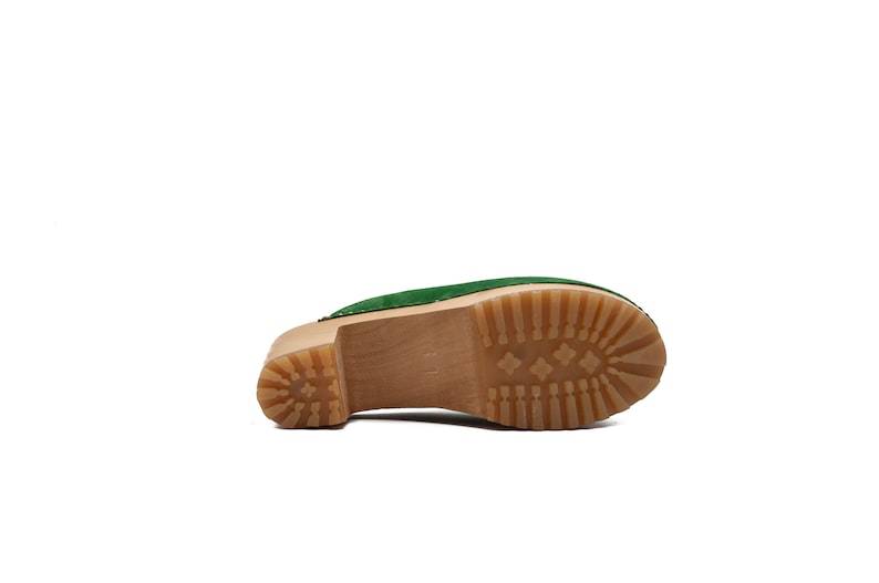 Puede incluir: Zueco de ante verde con plataforma de madera y suela de goma marr&oacute;n.