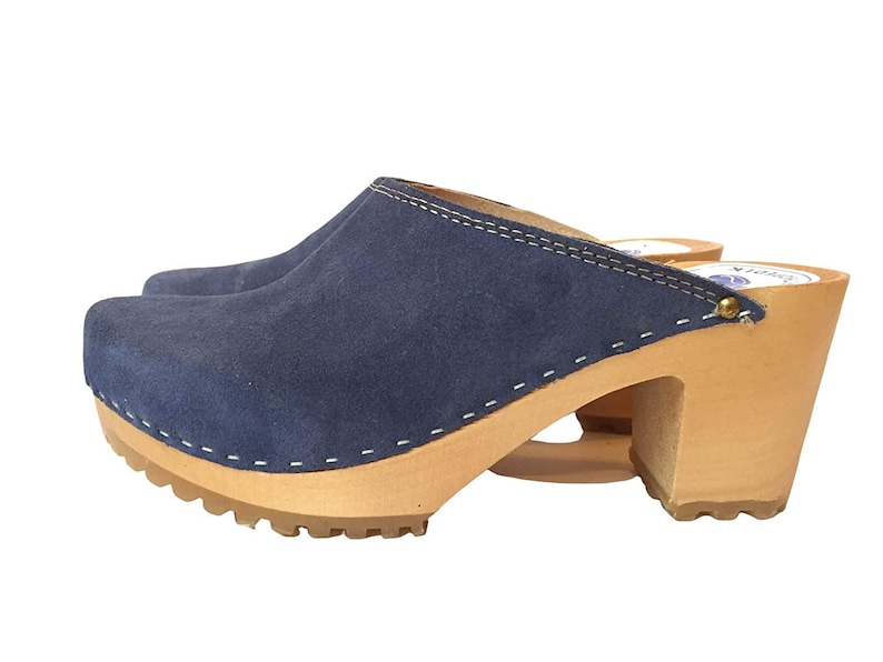 May include: Blue suede clogs with a wooden platform and heel. The clogs have a white stitch detail around the edge of the suede.