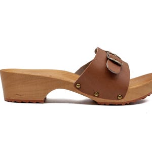 A single brown leather clog with a wooden sole and a buckled strap, viewed from the right side.