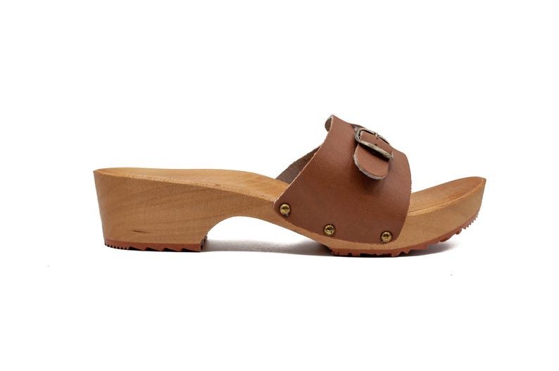 A single brown leather clog with a wooden sole and a buckled strap, viewed from the right side.