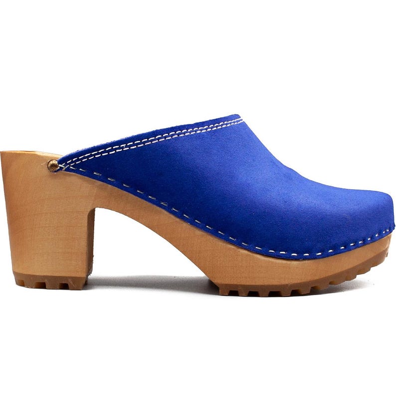 May include: Blue suede clogs with a wooden heel and platform. The clogs have a white stitch detail around the top edge.
