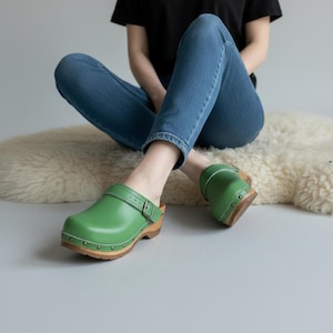 Zuecos de cuero verde, mules de madera con tachuelas antiguas y correa con hebilla.