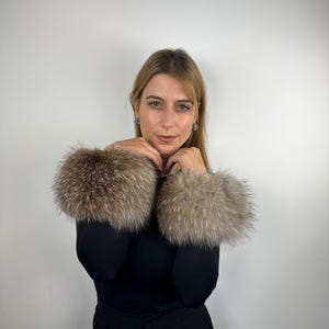 Puede incluir: Una mujer con una camisa negra de manga larga y pantalones negros con puños de piel marrón.