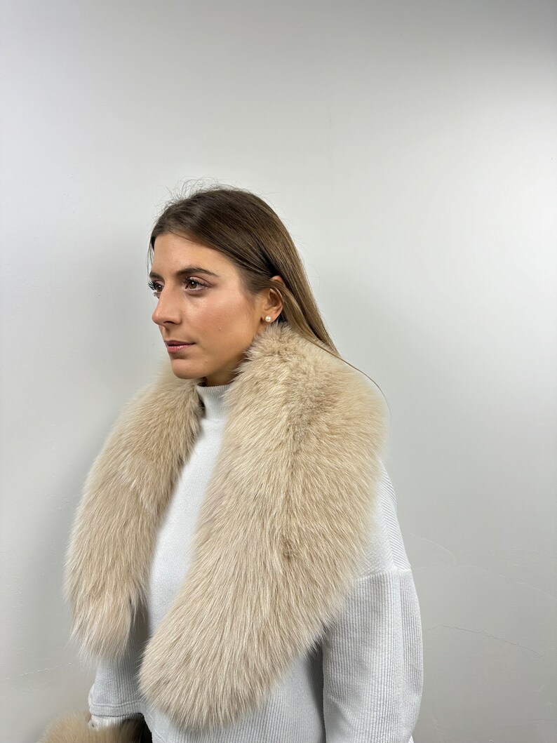 May include: A light beige fur collar with a long, flowing design. The collar is made of soft, fluffy fur and is perfect for adding a touch of luxury to any outfit.