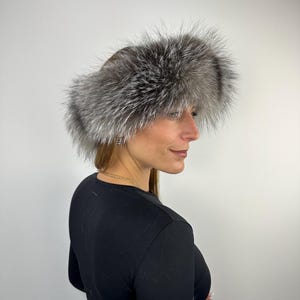 Könnte beinhalten: Ein Ohrenschutzband aus Silberfuchs-Fell. Das Band ist aus weichem, flauschigem Fell gefertigt und wurde entwickelt, um Ihre Ohren bei kaltem Wetter warm zu halten.