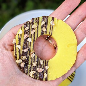 May include: A yellow pineapple ring topped with chocolate and chopped nuts.