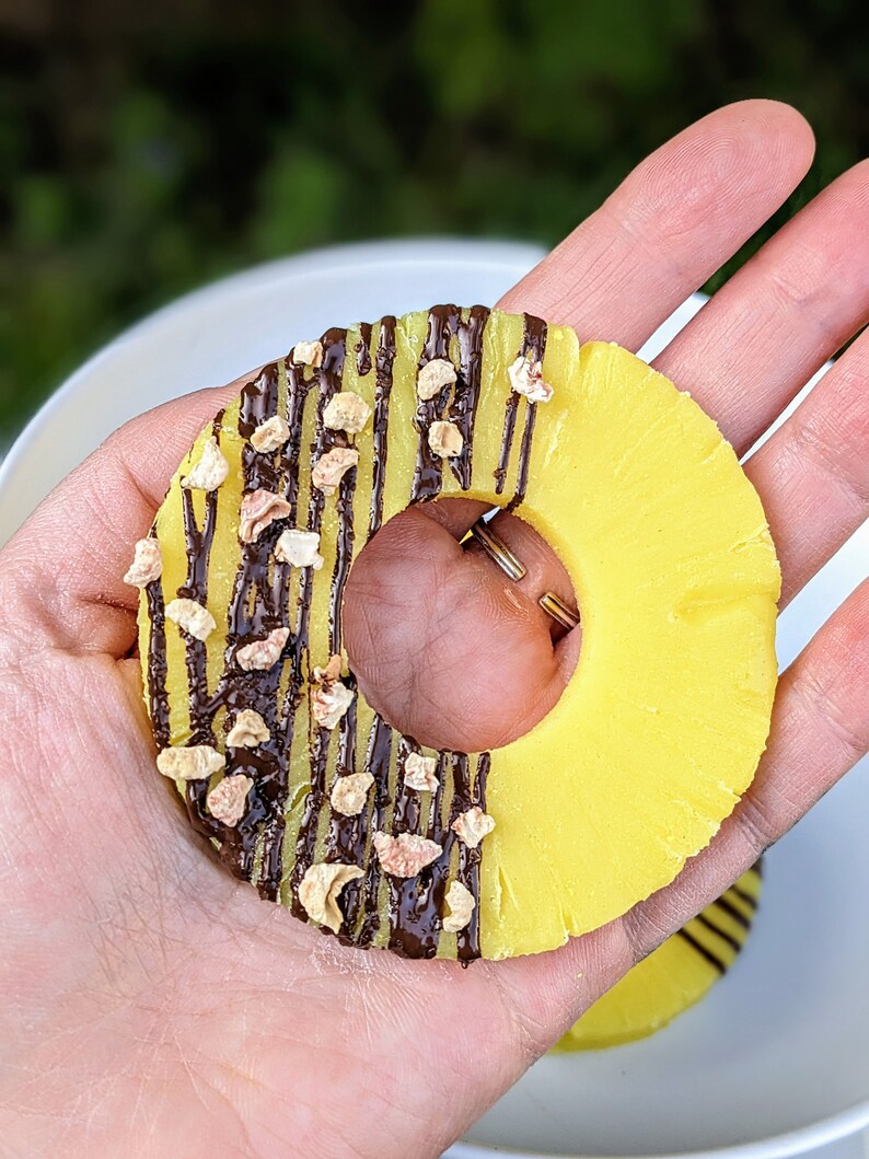 May include: A yellow pineapple ring topped with chocolate and chopped nuts.