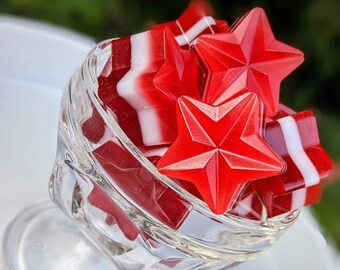 May include: A glass bowl filled with red and white star-shaped candies. The candies are arranged in a cluster, with the red stars on top.