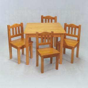 Pode incluir: Um conjunto de quatro cadeiras de madeira e uma mesa quadrada de madeira. As cadeiras e a mesa são todas de cor castanho claro. As cadeiras têm costas e assentos de ripas.