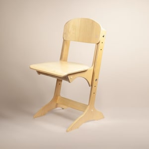 Könnte beinhalten: Ein hellfarbiger Holzhochstuhl mit geschwungener Rückenlehne und Sitzfläche. Der Stuhl hat ein einzigartiges Design mit abgewinkelten Beinen und verstellbaren Funktionen. Der Stuhl ist aus hellfarbigem Holz gefertigt und für ein Kind geeignet.