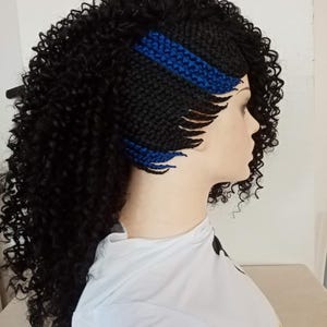 Può includere: Parrucca riccia nera con base nera intrecciata e dettagli blu. La parrucca è acconciata su una testa di manichino, evidenziando la consistenza e il volume dei capelli. Progettata come accessorio moda.
