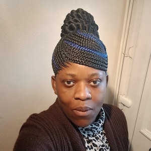 Peut inclure: Coiffure tressée avec des mèches noires et bleues, coiffée en un chignon haut. La personne porte un cardigan marron sur un haut à motifs léopard.