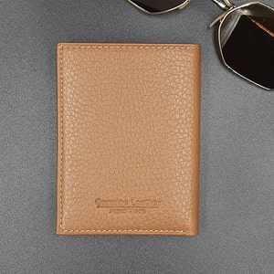 May include: A brown leather wallet with a stitched border and the text "Genuine Leather Hand Made" embossed on the front.