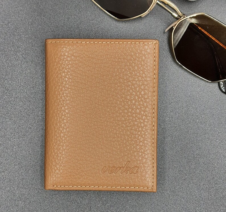 May include: A brown leather wallet with the word "verka" embossed on the front.