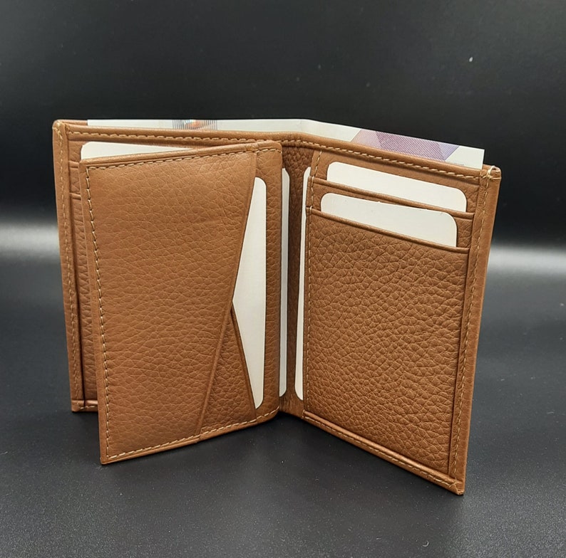 May include: A brown leather wallet with multiple card slots and a billfold. The wallet is open to show the interior.