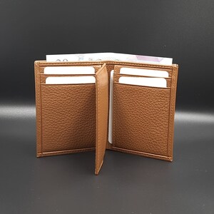 May include: A brown leather wallet with multiple card slots and a billfold. The wallet is open and empty.