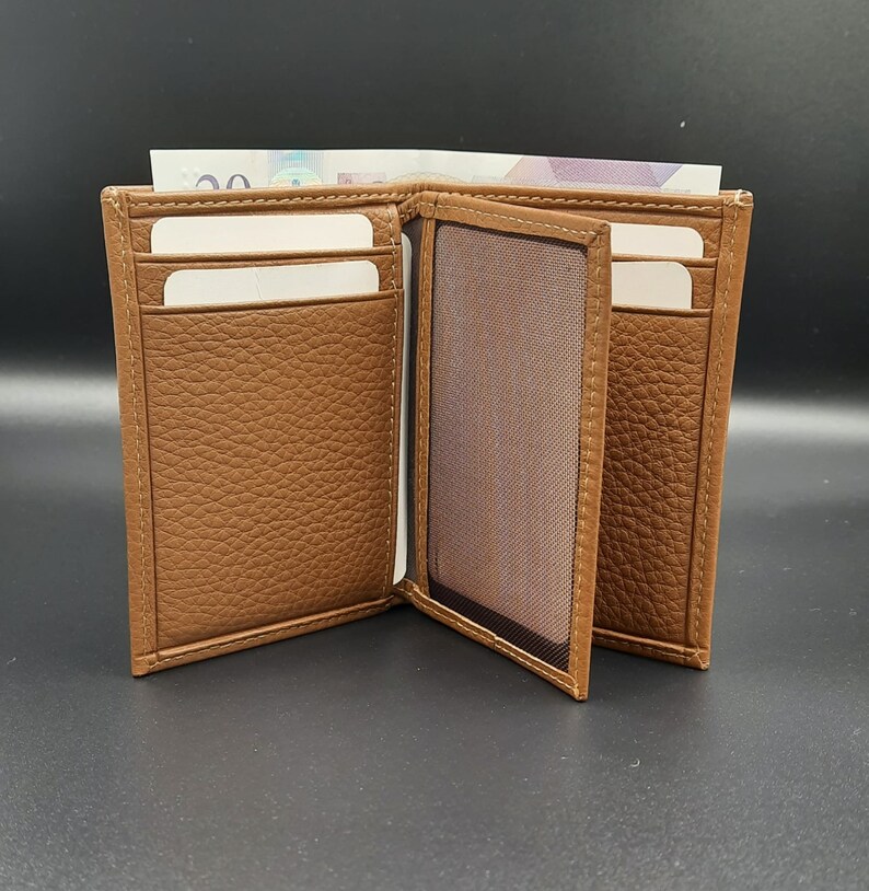 May include: A brown leather wallet with multiple card slots and a clear ID window. The wallet is open and has a billfold.