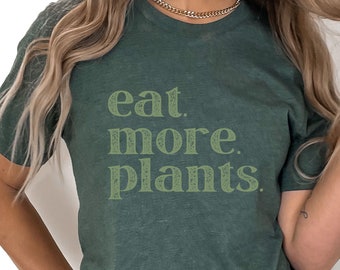 Puede incluir: Una camiseta verde con el texto "eat more plants." impreso en verde claro.