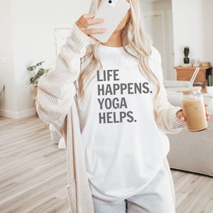 May include: White t-shirt with the text "Life Happens. Yoga Helps." printed in grey.