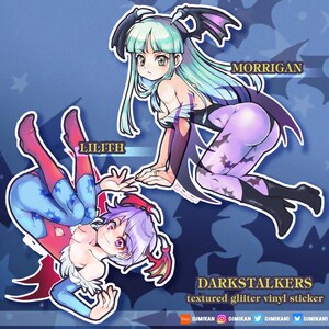 May include: A textured glitter vinyl sticker featuring two anime-style characters, Morrigan and Lilith, from Darkstalkers. Morrigan has teal hair and wears a black outfit with bat wing accents. Lilith has purple hair and a blue and red outfit. The sticker has a blue background.