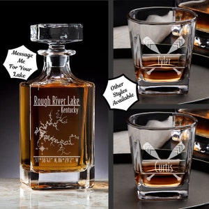 May include: A personalized crystal decanter with a map of Rough River Lake, Kentucky, and the coordinates 37°36′41″ N, 86°29′2" W. The decanter is engraved with the text "Rough River Lake, Kentucky". Two personalized square-shaped whiskey glasses are also shown, one with the name "Tyler" and the other with the name "Curtis".