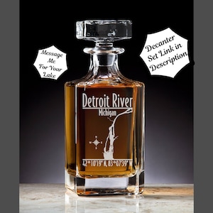 May include: A clear glass decanter filled with amber liquid, featuring the words "Detroit River Michigan" and coordinates. The decanter has a square base and a square stopper. The text "Message Me For Your Lake" is also visible.