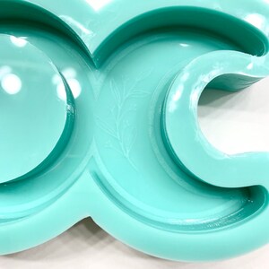 Puede incluir: Un molde de silicona verde claro con forma de media luna con un peque&ntilde;o dise&ntilde;o de hoja. El molde est&aacute; dise&ntilde;ado para hacer manualidades de resina.