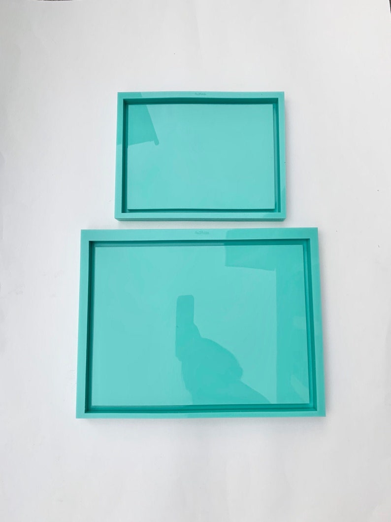 May include: Two turquoise rectangular silicone trays, one smaller than the other, on a white surface.
