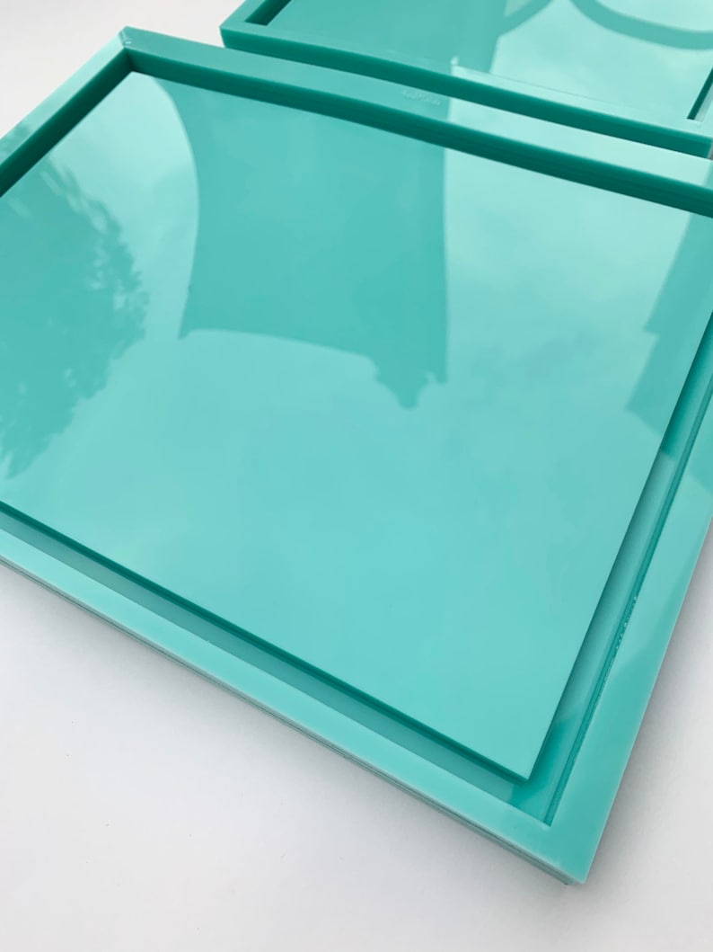 May include: A set of two teal rectangular trays with a raised edge. The trays are stacked on top of each other.