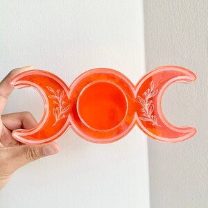 Puede incluir: Plato de resina naranja de triple luna con dise&ntilde;o floral blanco.