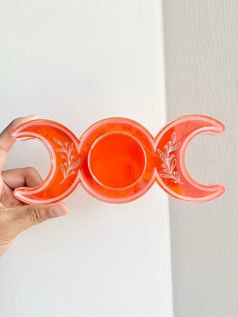 Puede incluir: Plato de resina naranja de triple luna con dise&ntilde;o floral blanco.