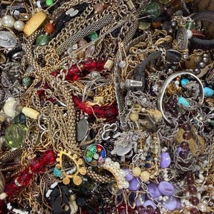 Pode incluir: Uma vista de perto de uma cole&ccedil;&atilde;o de v&aacute;rios colares, pulseiras e brincos. As joias incluem correntes de ouro e prata, colares de contas em vermelho, verde e roxo e fios de p&eacute;rolas. H&aacute; tamb&eacute;m v&aacute;rios an&eacute;is e pingentes.