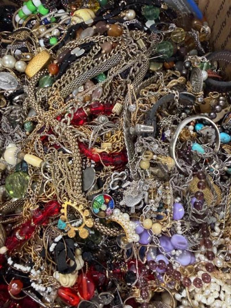 Pode incluir: Uma vista de perto de uma cole&ccedil;&atilde;o de v&aacute;rios colares, pulseiras e brincos. As joias incluem correntes de ouro e prata, colares de contas em vermelho, verde e roxo e fios de p&eacute;rolas. H&aacute; tamb&eacute;m v&aacute;rios an&eacute;is e pingentes.