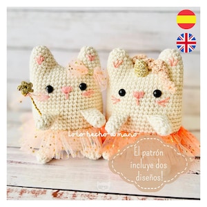 May include: Two crocheted white cat plushies wearing pink tutus with gold glitter. One cat has a pink bow and the other has a gold unicorn horn. The text "El patrón incluye dos diseños!" is in the image.