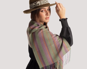 May include: A woman wearing a green and purple striped scarf with fringe, a brown hat with a patterned band, and a black dress.