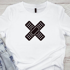 May include: White t-shirt with a black graphic of two crossed band-aids.